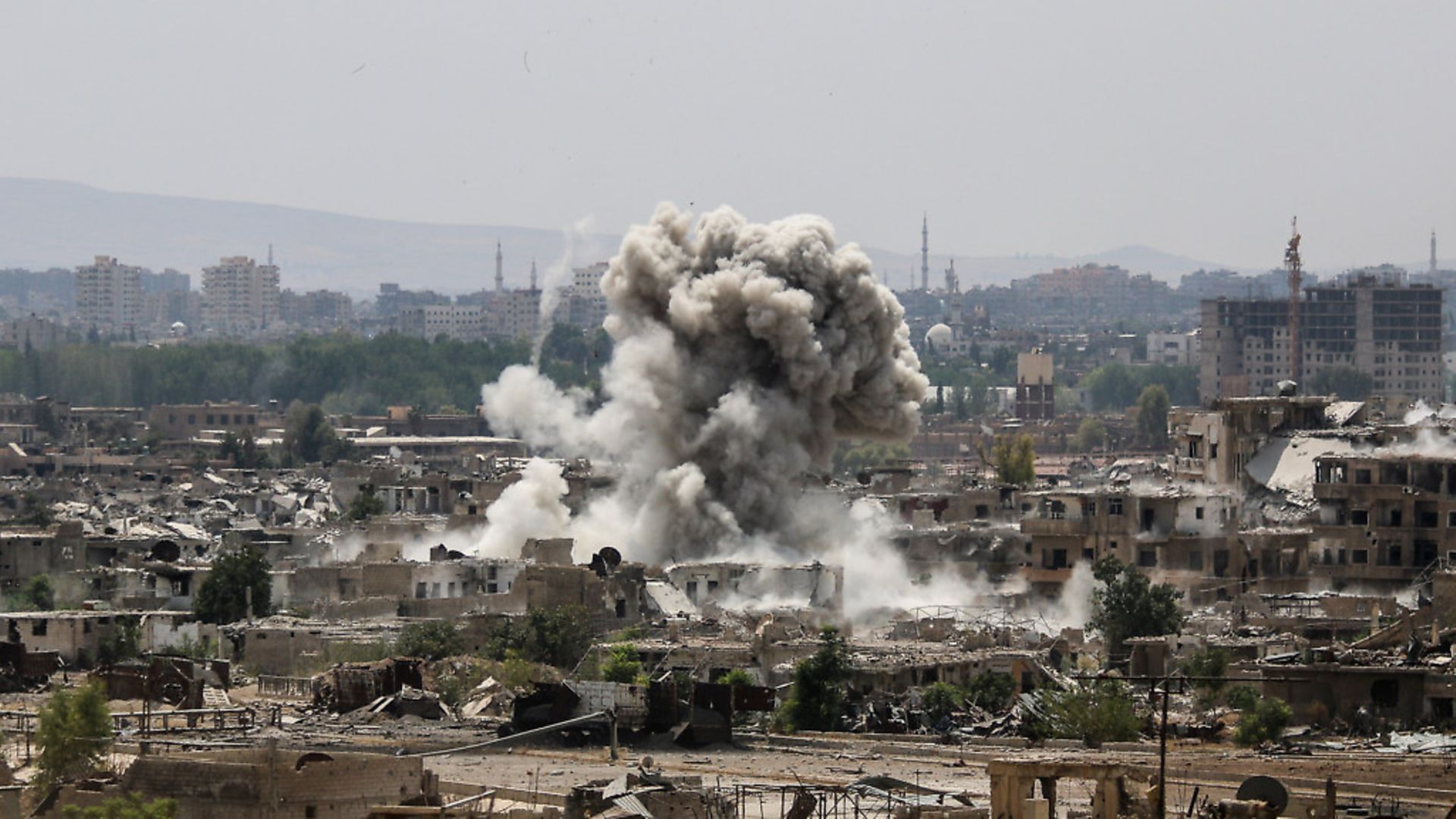 A huge explosion sends clouds into the air after Assad regime forces carried out air and ground strikes in the Eastern Ghouta region of Damascus, Syria on August 20. Photo: Ammar Al-Bushy/Anadolu Agency/Getty Images - Credit: Getty Images