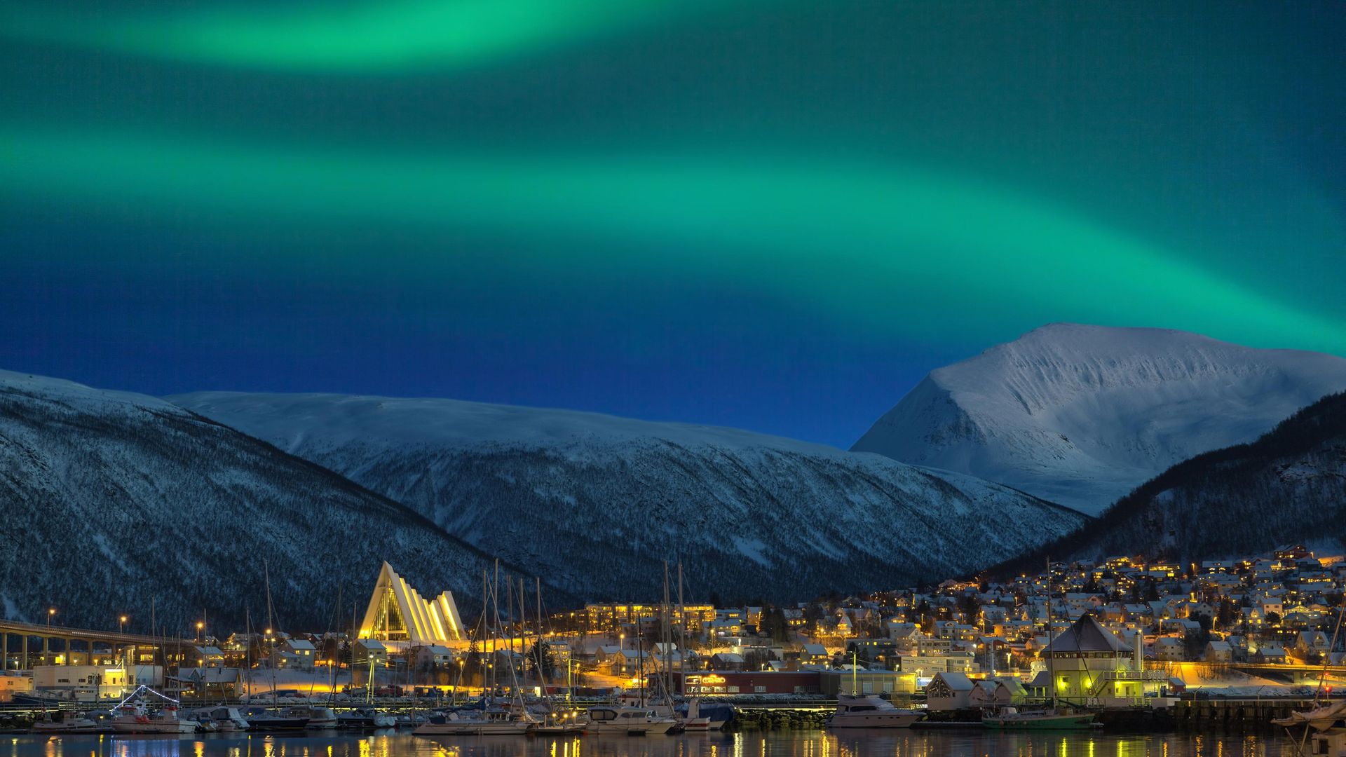 The view at night on illuminated Tromso city with cathedral and majestic aurora borealis - Credit: Getty Images