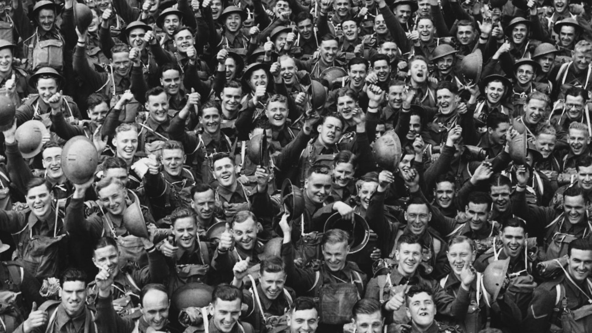 A large crowd of young English soldiers cheering as they wait to leave for France during the Second World War - Credit: Corbis via Getty Images