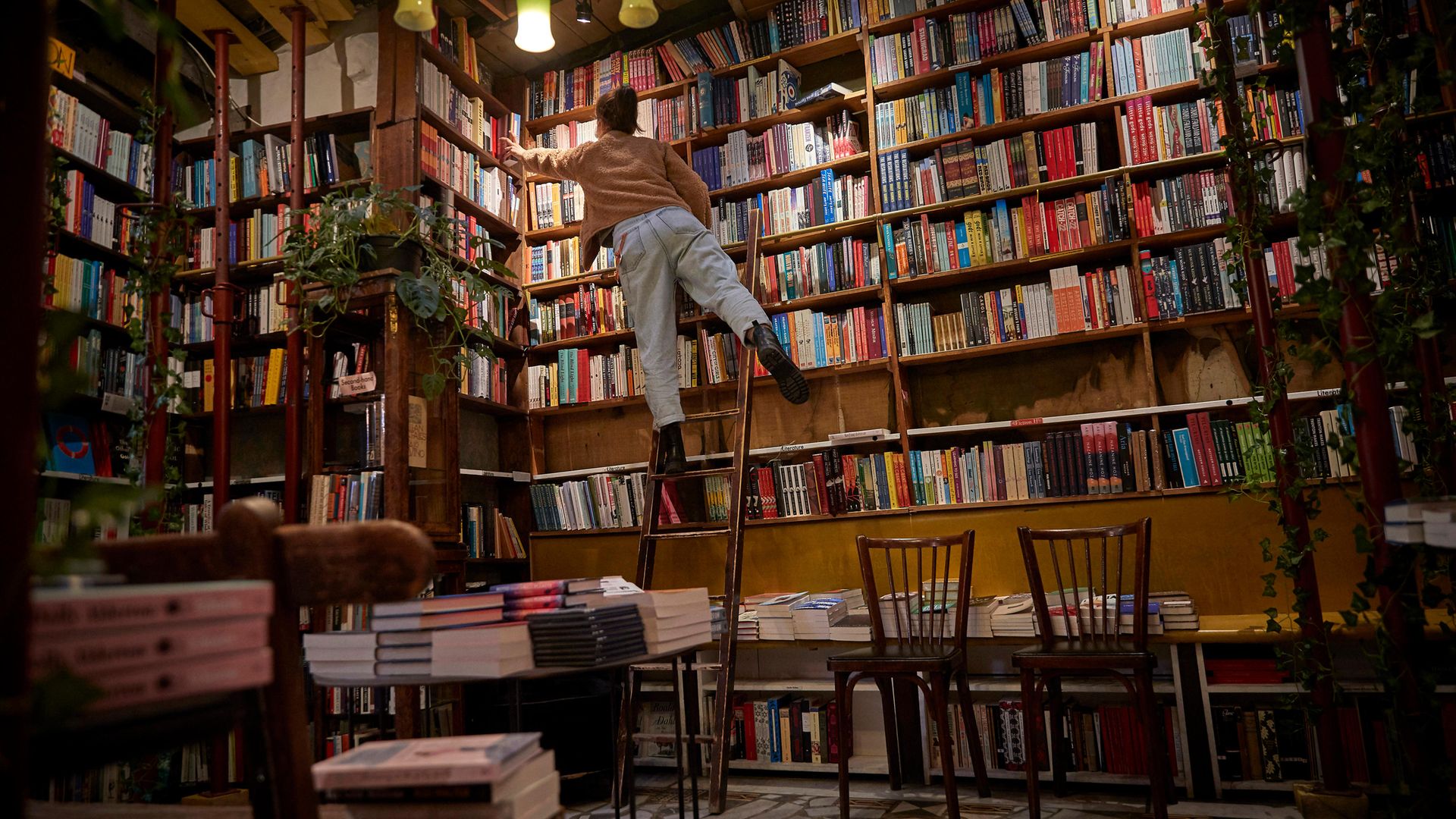 A staff member picks out a book for an order inside an otherwise deserted Shakespeare & Co, in Paris - Credit: Getty Images