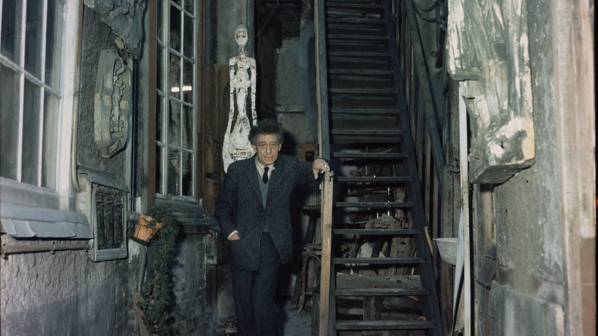 Alberto Giacometti stands in the stairwell to his house, where the walls are decorated with his sculptures, 1958 - Credit: Corbis/VCG via Getty Images