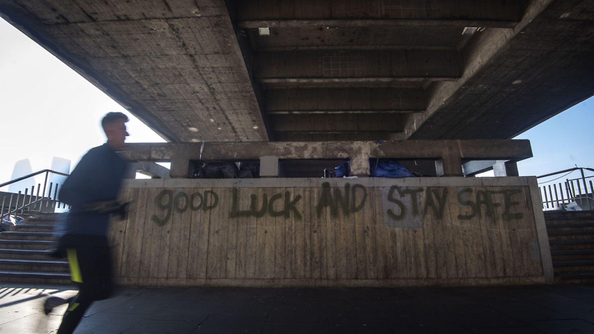 A man runs past graffiti reading 'good luck and stay safe' underneath Waterloo Bridge in Westminster, London. Photograph: Victoria Jones/PA Wire. - Credit: PA