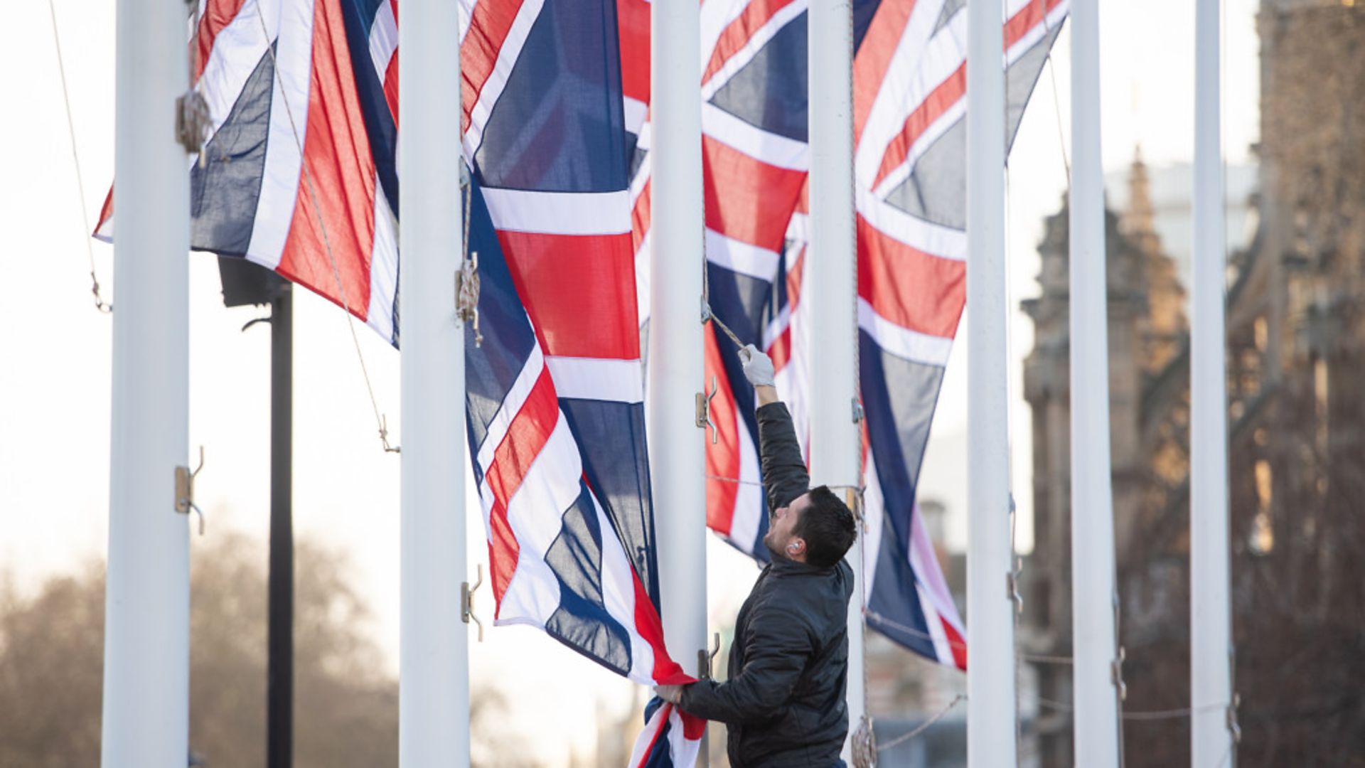 A worker removes Union flags from flagpoles in Parliament Square, London - Credit: PA