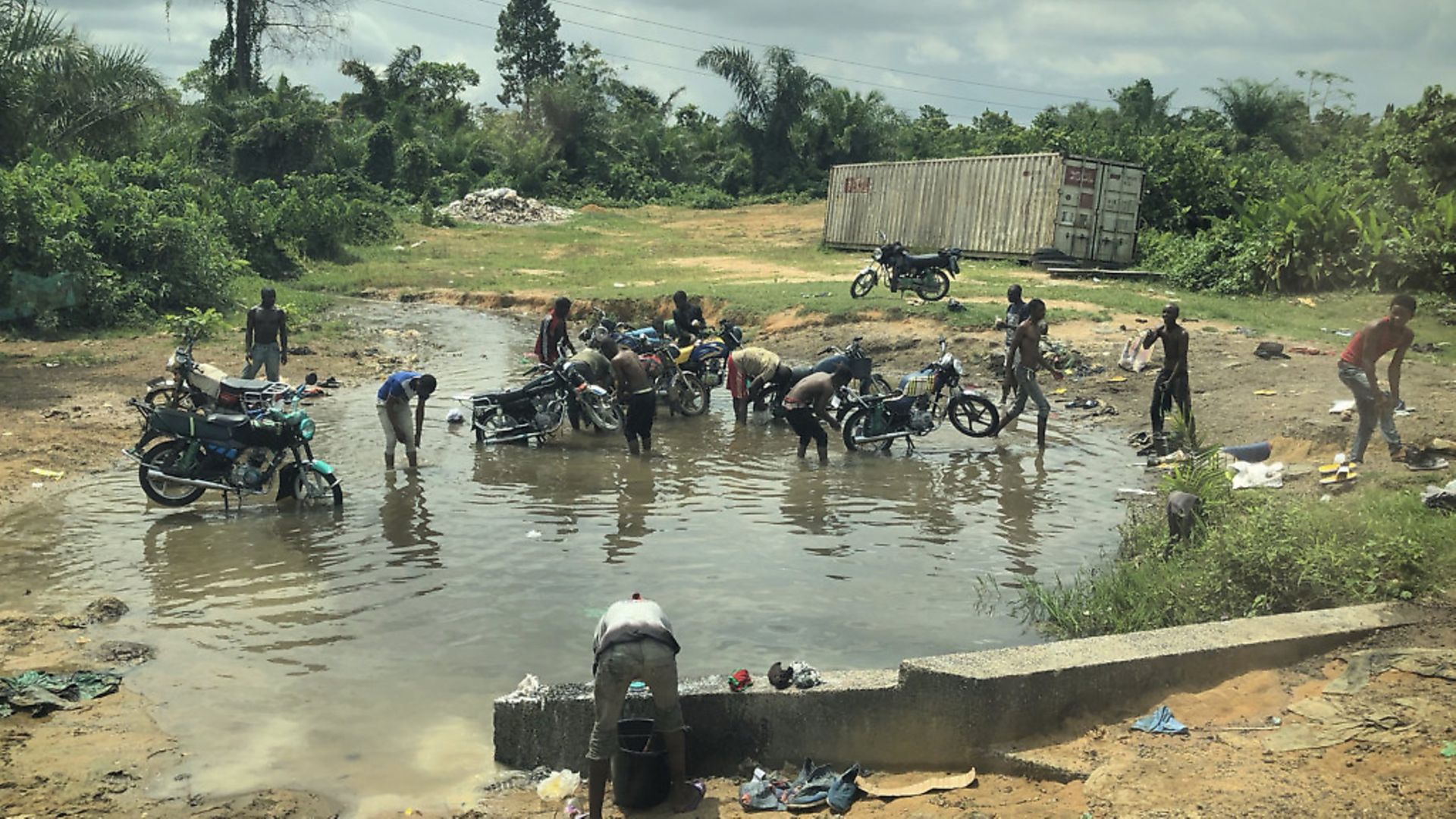 Men wash their motorbikes in a water hole near the border of Anglophone region in Cameroon.Picture: Giles Clarke/UNOCHA via Getty Images - Credit: UNOCHA via Getty Images