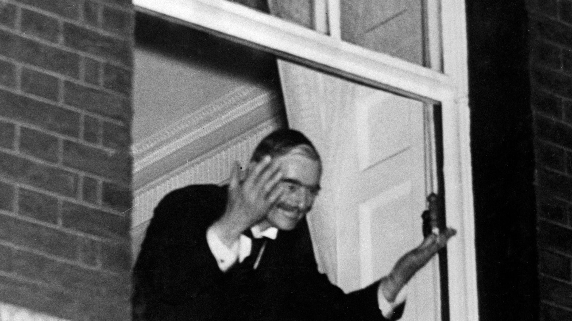 Neville Chamberlain waves to crowds from the window of No.10 after the Munich Agreement was signed. - Credit: PA