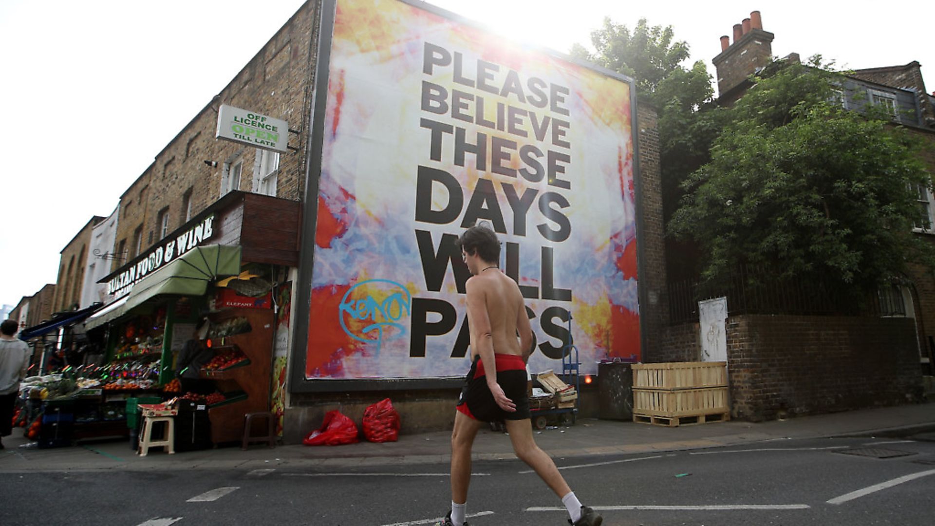 A man walks past a large billboard reading 'Believe me, these days will pass' at London Fields on May 07, 2020 in London, England. The UK is continuing with quarantine measures intended to curb the spread of Covid-19, but as the infection rate is falling government officials are discussing the terms under which it would ease the lockdown. (Photo by Alex Pantling/Getty Images) - Credit: Getty Images