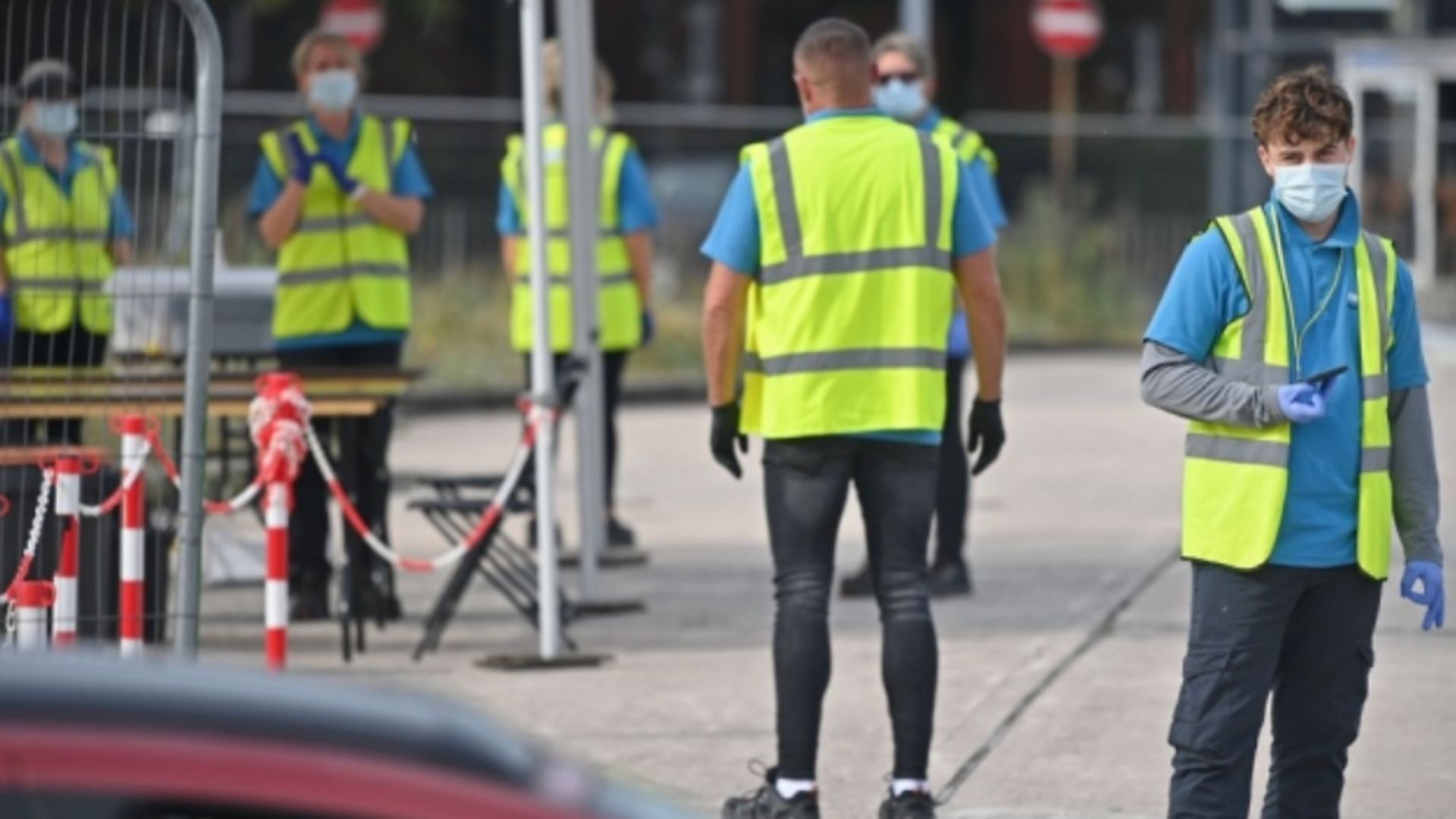 Workers wear NHS Test and Trace branded Hi-Vis jackets as they work at a COVID-19 testing centre. Photo: Paul ELLIS / AFP via Getty Images - Credit: Paul ELLIS / AFP via Getty Images