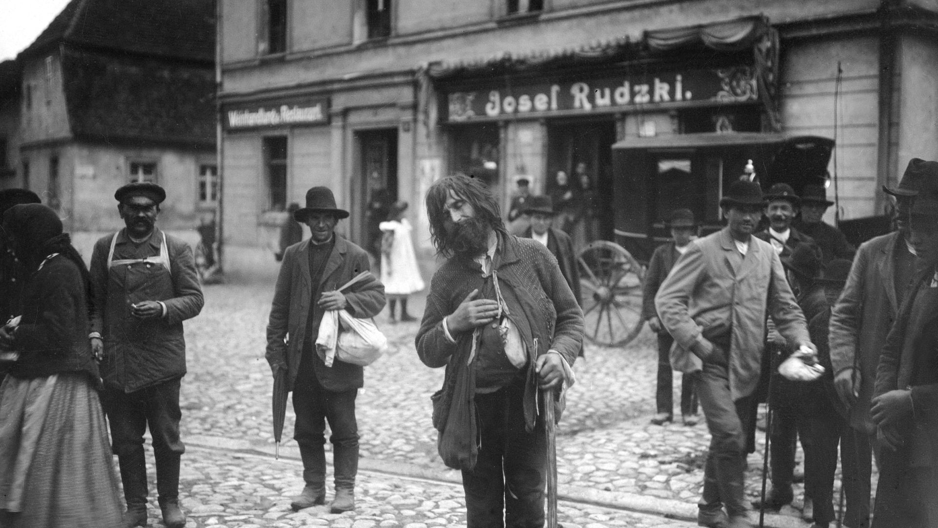 Locals stare at a beggar in the street in Posen, Prussia - now part of Poland - in a photograph from 1910 - Credit: ullstein bild via Getty Images