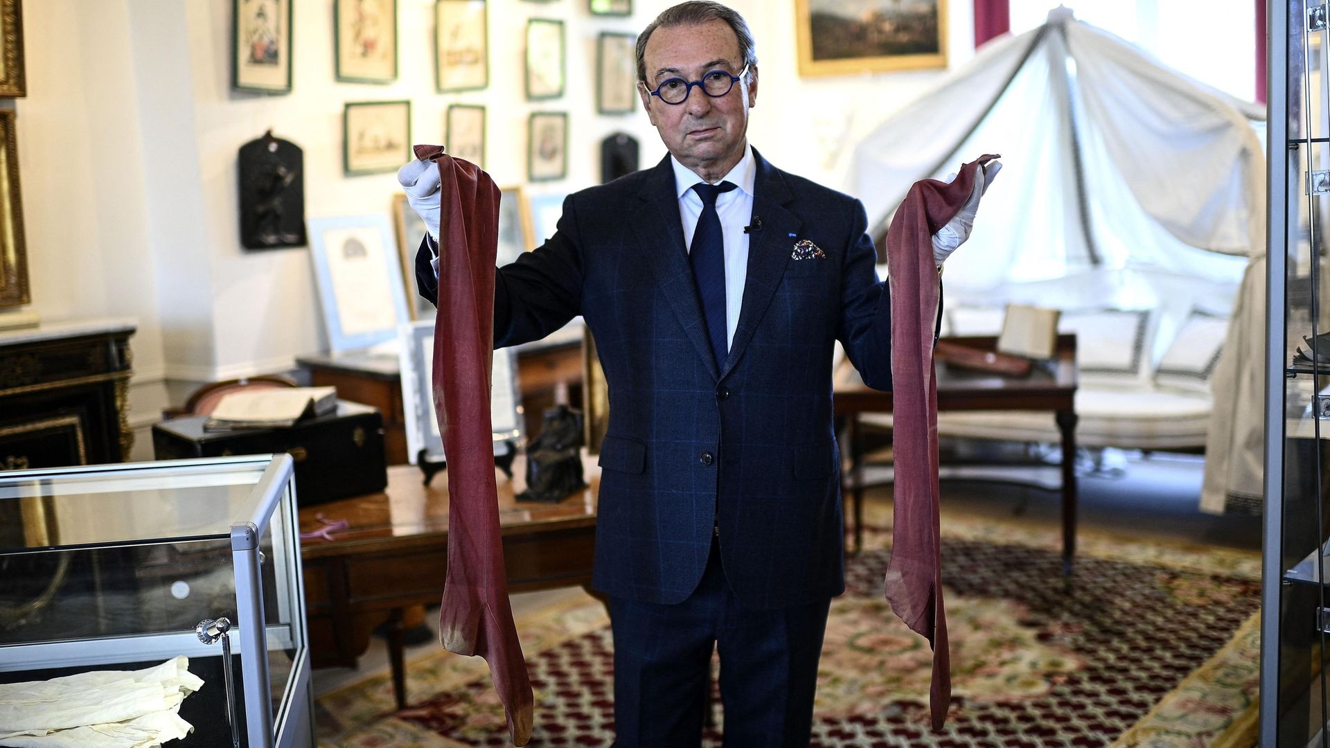 Auctioneer Jean-Pierre Osenat holds a pair of stockings that belonged to Napoleon - Credit: Photo by CHRISTOPHE ARCHAMBAULT/AFP via Getty Images