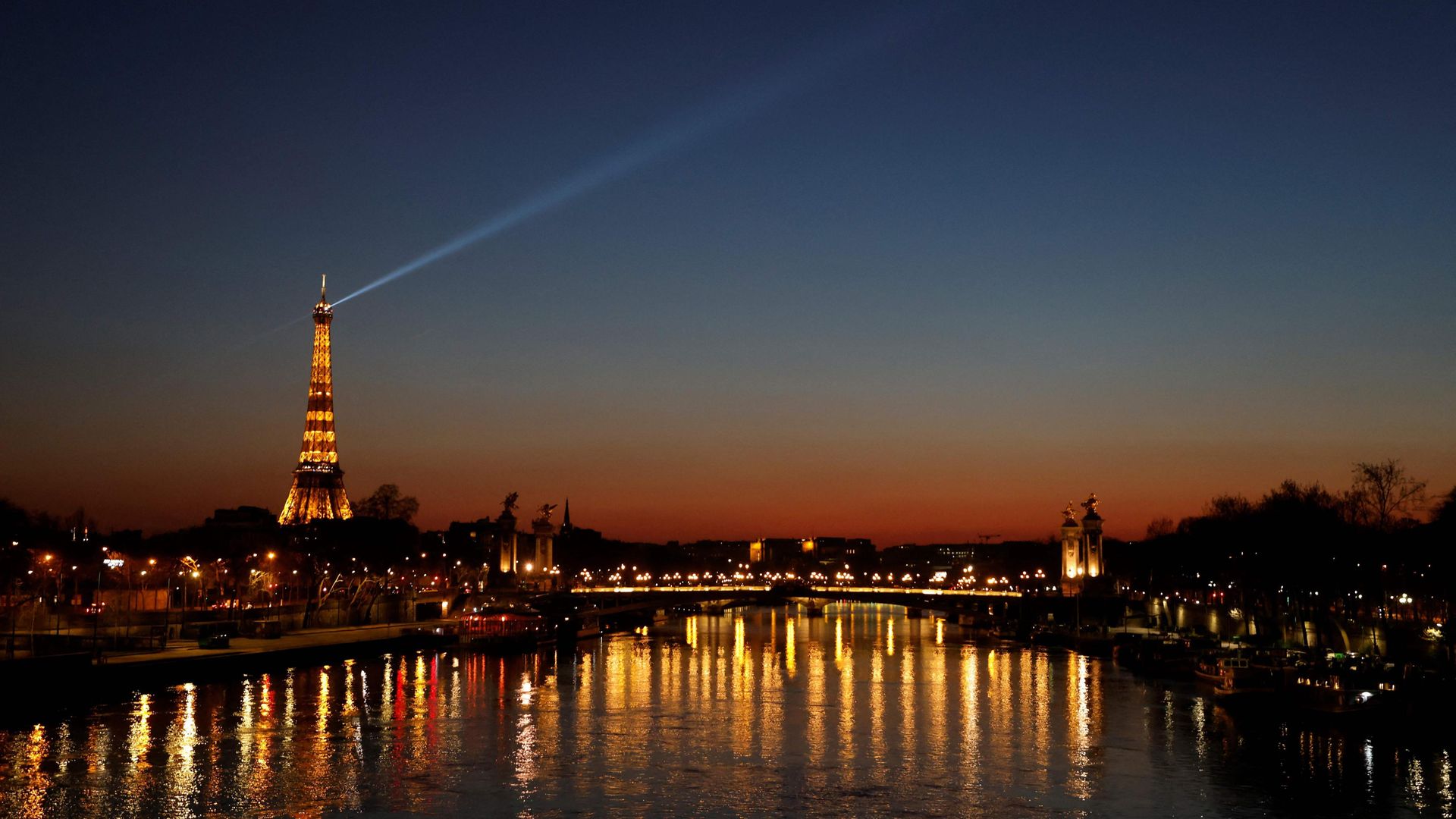 A spotlight shines from the Eiffel Tower at sunset, in March 2021 - Credit: AFP via Getty Images