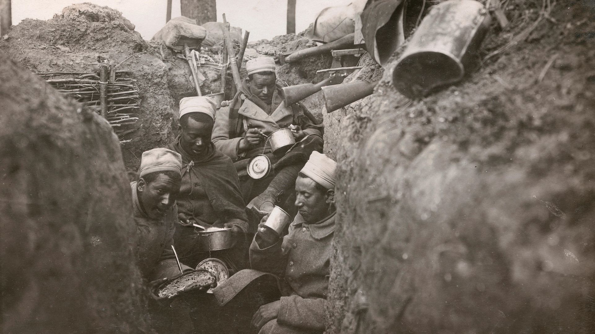 Senegalese infantrymen in the French army eat in their trench, in a photograph from 1915 - Credit: Corbis via Getty Images