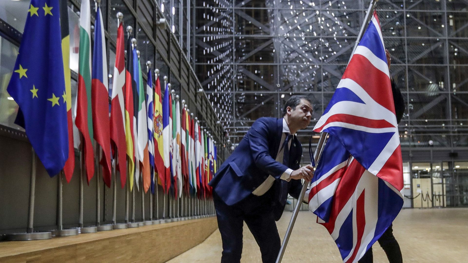 EU Council staff members remove the United Kingdom's flag from the European Council building in Brussels - Credit: POOL/AFP via Getty Images