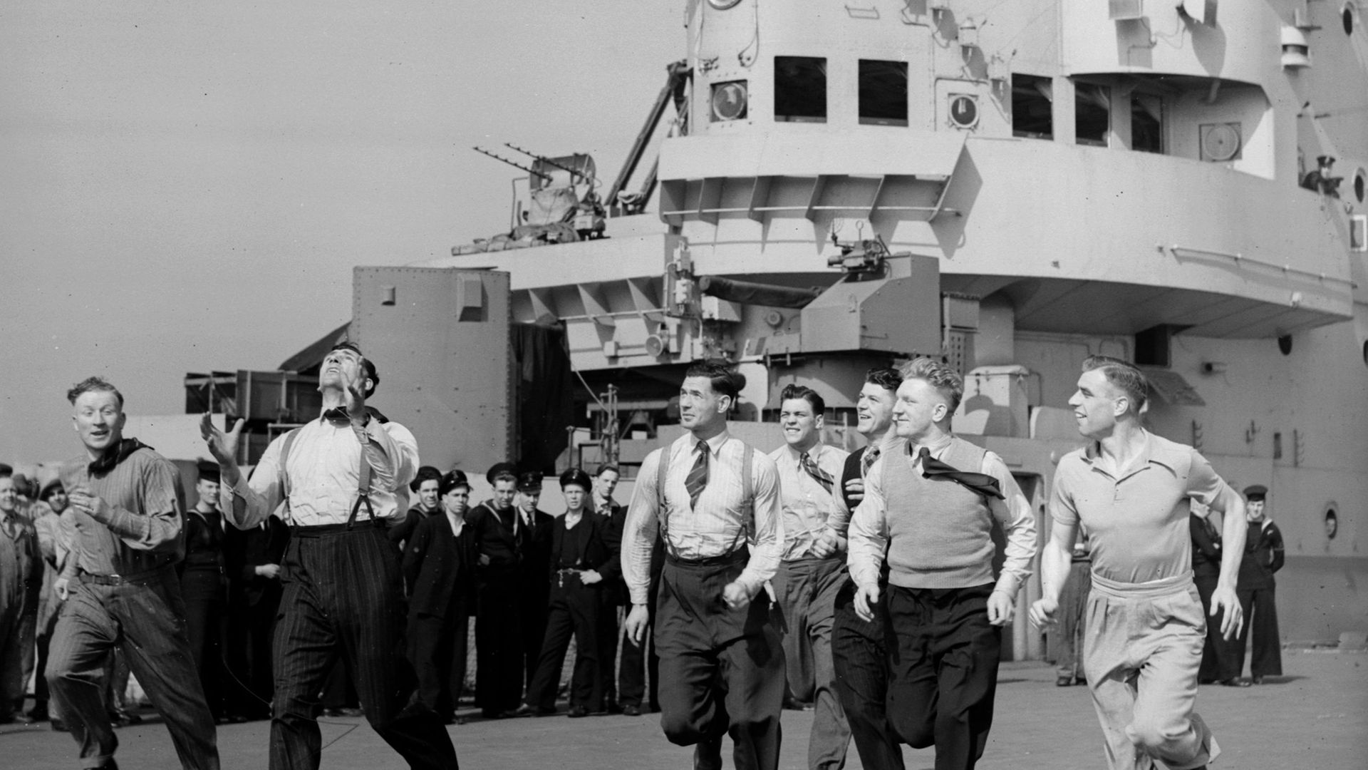 The British Lions rugby league team toss a ball around on the deck of the aircraft carrier HMS Indomitable, bound for Australia - Credit: Getty Images