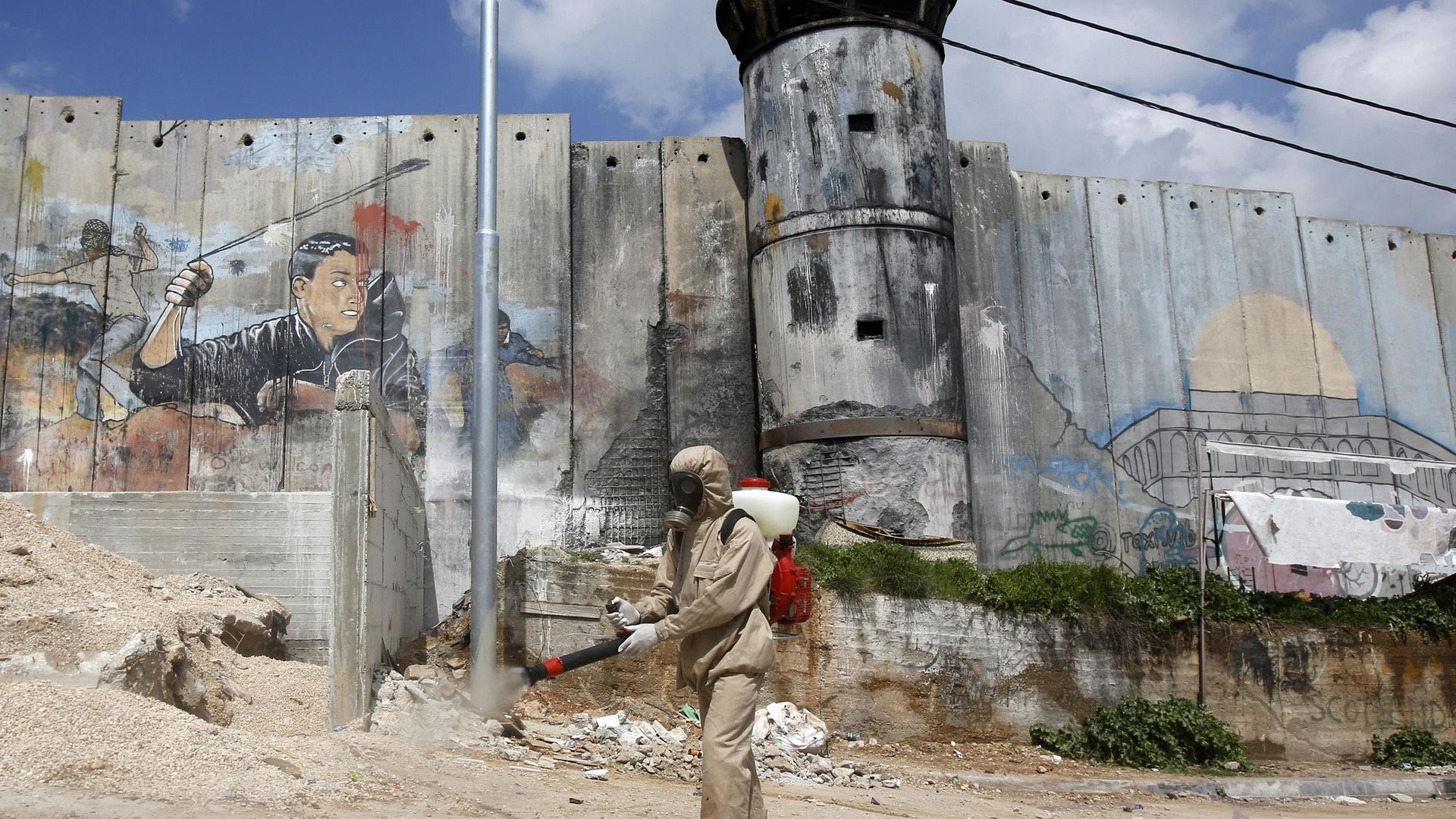 Bedlam or Bethlehem? In this apocalyptic image, a Palestinian sanitary department worker sprays disinfectant along a security border in Bethlehem, during the pandemic - Credit: AFP via Getty Images