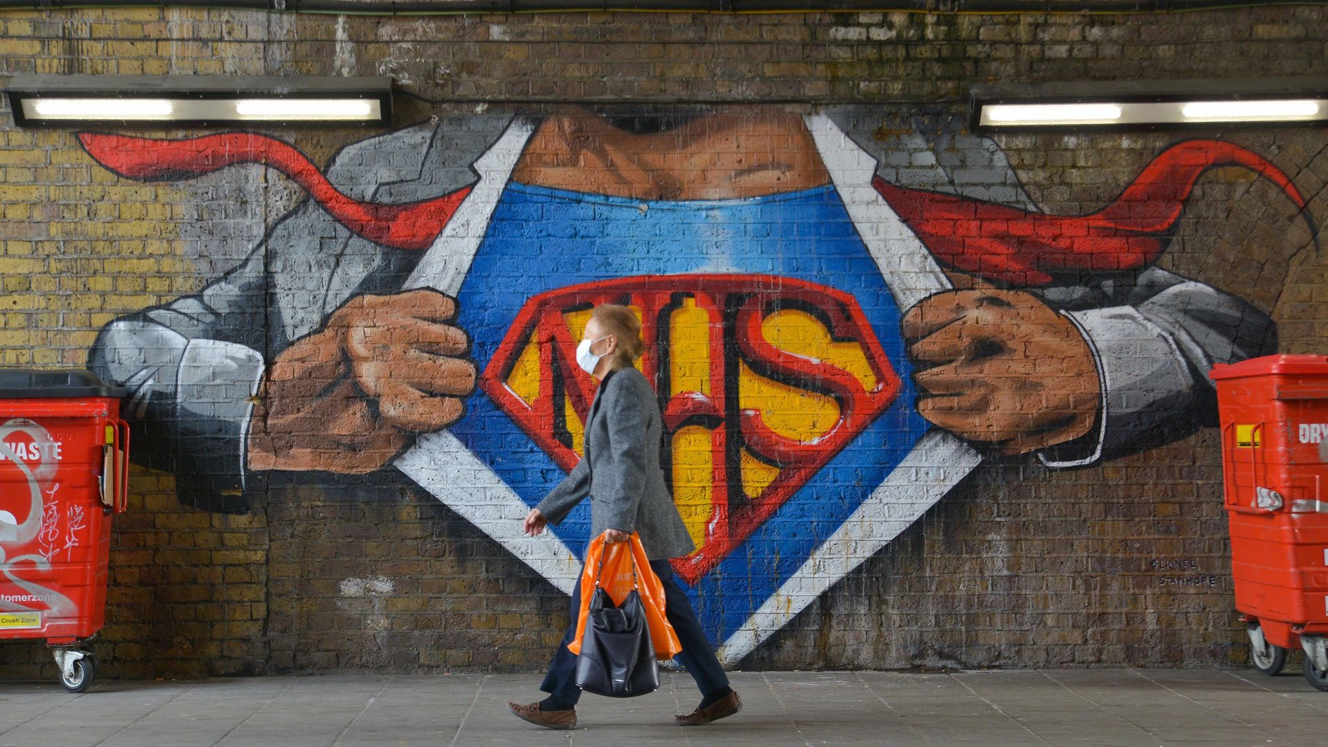 A woman wearing a face mask as a precaution against the spread of Covid-19 walks past a graffiti tribute to the NHS in Waterloo, London - Credit: Photo by Thomas Krych/SOPA Images/LightRocket via Getty Images